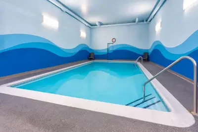 a swimming pool in a room with a wave painted on the wall at Ramada by Wyndham Coquitlam in Coquitlam