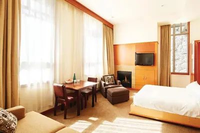 a hotel room with a bed and a table and chair at Pan Pacific Whistler Village Centre in Whistler