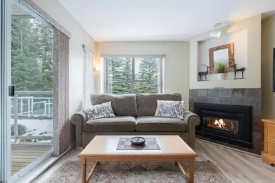 a living room with a couch and a fireplace at Wildwood Lodge by Outpost Whistler in Whistler