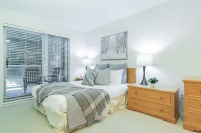 a white bedroom with a bed and a window at Wildwood Lodge by Outpost Whistler in Whistler