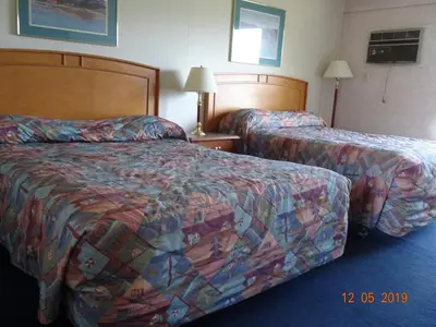 a hotel room with two beds and two lamps at Hospitality Inn in Kamloops