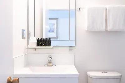 a white bathroom with a sink and a mirror at Robin Hood Inn and Suites in Victoria