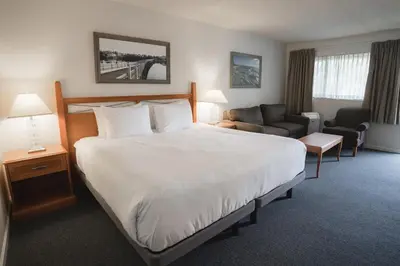 a hotel room with a large bed and a couch at Robin Hood Inn and Suites in Victoria