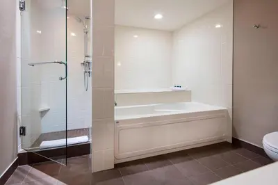 a bathroom with a shower and a tub and a toilet at Delta Hotels by Marriott Edmonton South Conference Centre in Edmonton
