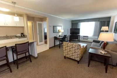 a living room with a couch a table and a kitchen at Campus Tower Suite Hotel in Edmonton