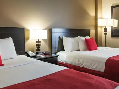 a hotel room with two beds with red pillows at Paradise Inn & Conference Centre in Grande Prairie