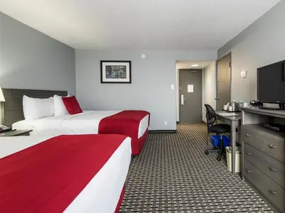 a hotel room with two beds and a desk at Paradise Inn & Conference Centre in Grande Prairie