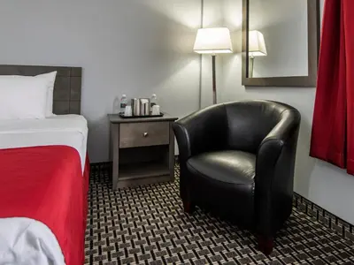 a hotel room with a black chair and a bed at Paradise Inn & Conference Centre in Grande Prairie