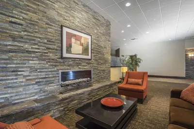 a living room with a stone wall with a fireplace at Quality Hotel & Conference Centre in Fort McMurray