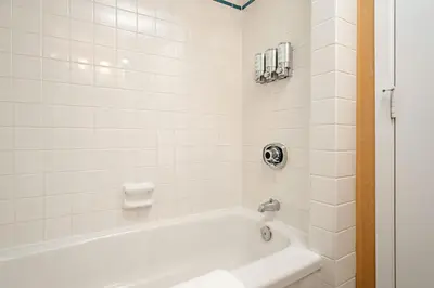 a white bath tub in a white tiled bathroom at Executive Hotel Vancouver Airport in Richmond