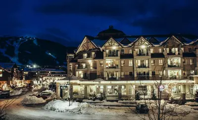 a large building in the snow at night at Summit Lodge Boutique Hotel by Paradox in Whistler