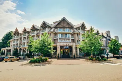 a large apartment building in a parking lot with trees at Summit Lodge Boutique Hotel by Paradox in Whistler