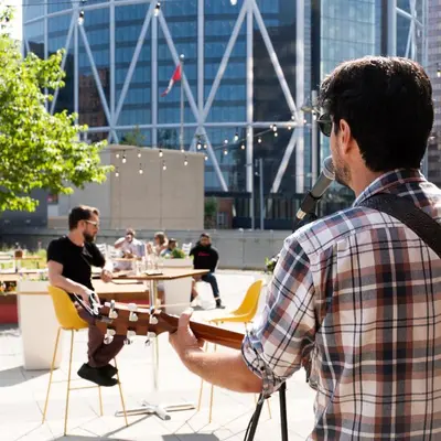a man playing an acoustic guitar in a courtyard at Delta Hotels by Marriott Calgary Downtown in Calgary