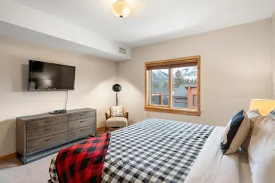 a bedroom with a bed and a flat screen tv at Spring Creek Penthouse by Canadian Rockies Vacation Rentals in Canmore