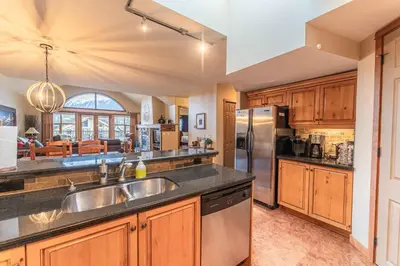 a kitchen with wooden cabinets and a stainless steel refrigerator at Cascade Penthouse by Canadian Rockies Vacation Rentals in Canmore