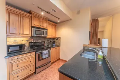 a kitchen with wooden cabinets and a black counter top at Cascade Penthouse by Canadian Rockies Vacation Rentals in Canmore