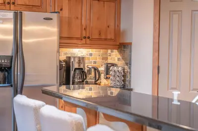 a kitchen with a stainless steel refrigerator and wooden cabinets at Cascade Penthouse by Canadian Rockies Vacation Rentals in Canmore