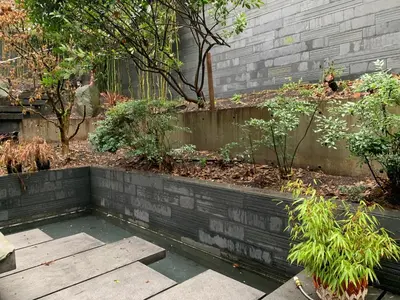 a garden with a retaining wall and some plants at White House in Vancouver