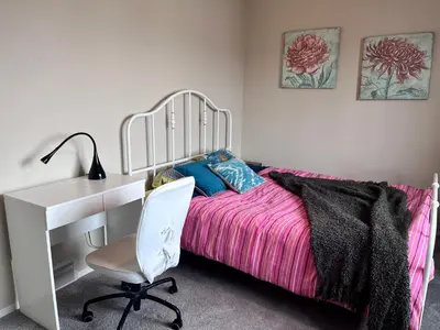 a bedroom with a white desk and a bed with a pink blanket at Banff -Calgary Garden &3 mins Bus station Close C-Train&Free Parking in Calgary