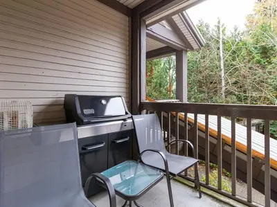 a grill on a screened in porch with a chair at Updated Townhouse in Village. Pool/Hot Tub/Parking in Whistler