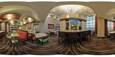a hotel lobby with a bar and tables and chairs at Homewood Suites Calgary Airport in Calgary