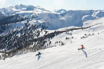 a group of people skiing down a snow covered slope at 2BR in Gleneagle, Gourmet Kitchen, Newly Updated, Wood Burning Fireplace, Parking in Whistler