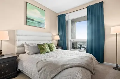a bedroom with a bed with blue curtains and a window at GlobalStay Downtown Calgary Condos in Calgary