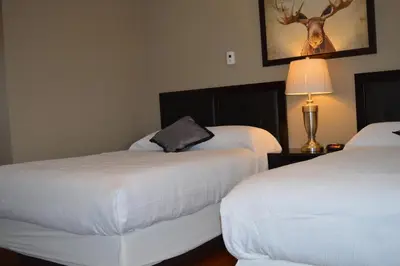 a hotel room with two beds and a deer on the wall at 94 Motel & RV Park in One Hundred Mile House