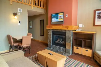 a living room with a fireplace and a dining table at Fox Hotel and Suites in Banff