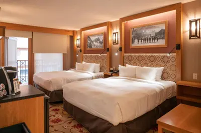 a hotel room with two beds and a television at Banff Ptarmigan Inn in Banff