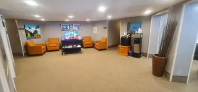 a waiting room with orange chairs and a tv at Bow View Lodge in Banff