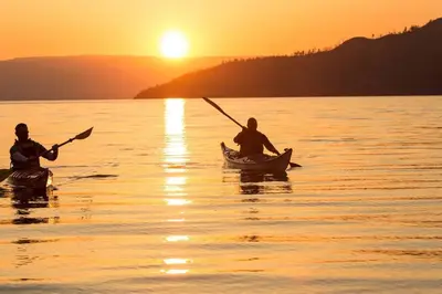 two people in kayaks on the water at sunset at Grandma's Elephant Hideaway in Penticton