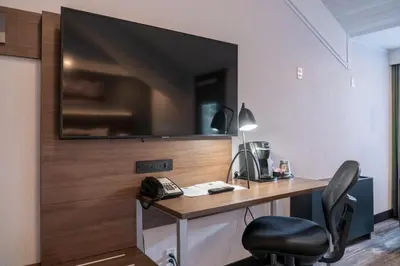a room with a desk with a television on a wall at Red Carpet Inn in Banff