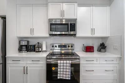 a kitchen with white cabinets and a stove and microwave at Luxury Spacious Private House near City Centre in Calgary