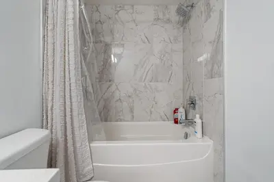 a bathroom with a white tub and a white shower curtain at Luxury Spacious Private House near City Centre in Calgary