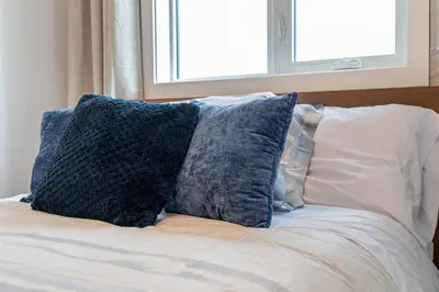 a bed with two pillows on it with a window at Contemporary Luxury 4 bedroom House near Downtown in Calgary
