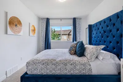a bedroom with a blue bed and a window at Modern House with Private Backyard & Fireplace in Calgary