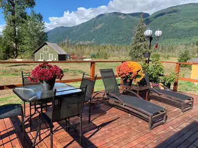 a deck with chairs and a table with flowers on it at The Country Barn in Port Alberni