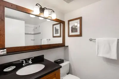 a bathroom with a sink and a mirror and a toilet at Tantalus Resort Lodge in Whistler