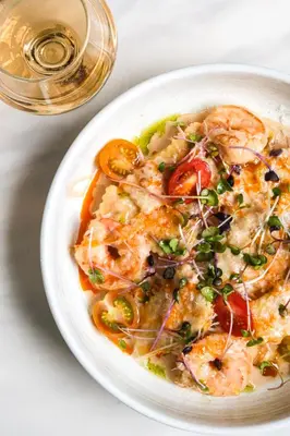 a white plate of food with shrimp and vegetables at Delta Hotels by Marriott Calgary South in Calgary