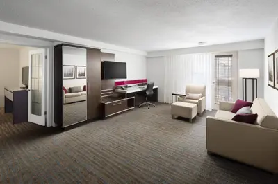 a hotel room with a bedroom with a couch and a desk at Delta Hotels by Marriott Calgary South in Calgary
