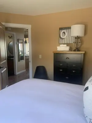 a bedroom with a bed and a dresser and a lamp at Exceptional Boutique Cottage with Incredible Lake View in Kelowna