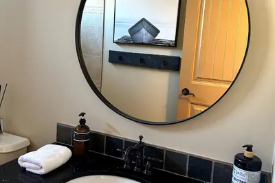 a bathroom with a mirror and a sink at Exceptional Boutique Cottage with Incredible Lake View in Kelowna