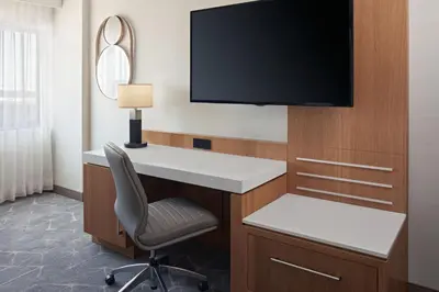 a room with a desk and a television on a wall at Delta Hotels Calgary Airport In-Terminal in Calgary