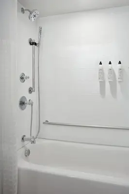 a white bath tub with a mirror and a shower at Delta Hotels Calgary Airport In-Terminal in Calgary