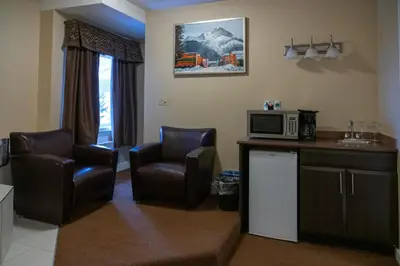 a living room with two chairs and a microwave at Irwin's Mountain Inn in Banff