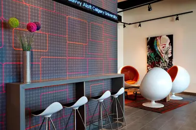 a room with stools and a wall with a painting at Aloft Hotel Calgary University in Calgary