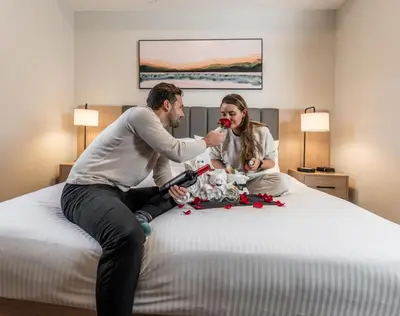 a man and woman sitting on a bed with a dog at Blackstone Mountain Lodge by CLIQUE in Canmore
