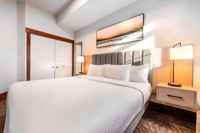 a hotel room with a large white bed and a window at Blackstone Mountain Lodge by CLIQUE in Canmore