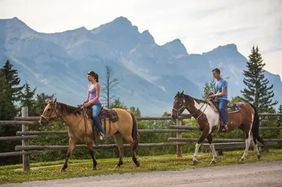 two people riding horses in front of a fence at Lodges at Canmore in Canmore